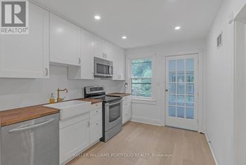 Toronto (Birchcliffe-Cliffside) apartment for rent - A kitchen with white cabinets and a wooden counter top.