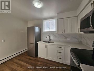 Kitchener apartment for rent - A kitchen with white cabinets and a stainless steel refrigerator.