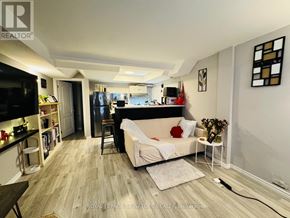 Toronto (Danforth Village-East York) apartment for rent - A living room with a couch, a television, and a kitchen area in the background.