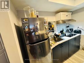 Toronto (Danforth Village-East York) apartment for rent - A kitchen with a stainless steel refrigerator and black cabinets.