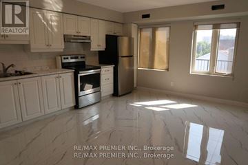 Toronto (Weston) multi-family for rent - A kitchen with white cabinets and a black stove top oven.