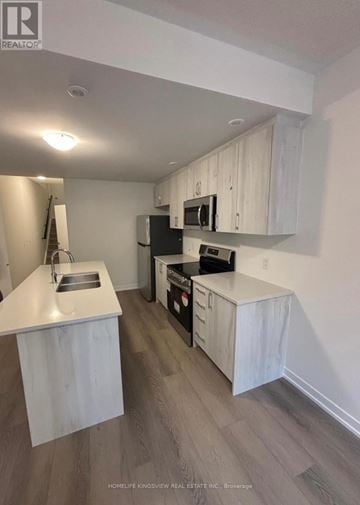 Clarington (Newcastle) townhouse for rent - A kitchen with white cabinets and a black refrigerator.