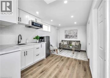 Waterloo apartment for rent - A well-lit kitchen with white cabinets and a grey sofa in the living room.