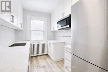 Niagara Falls (Cherrywood) multi-family for rent - A white kitchen with a refrigerator, microwave, and a window.