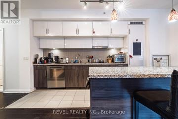 Toronto (Waterfront Communities) condo for rent - A modern kitchen with white cabinets and a stainless steel dishwasher.