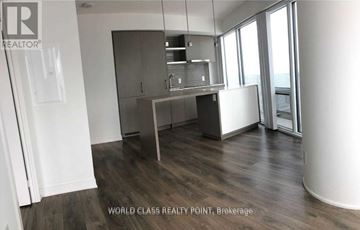 Toronto (Waterfront Communities) condo for rent - A real estate listing photo of a kitchen with wood floors and white walls.