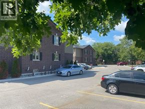 Lakeshore apartment for rent - A parking lot with cars and a building in the background.