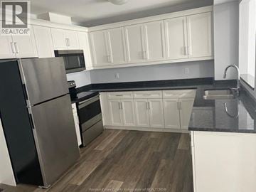Lakeshore apartment for rent - A kitchen with white cabinets and a black fridge.