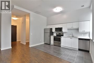 Hamilton condo for rent - A kitchen with white cabinets and a black fridge.