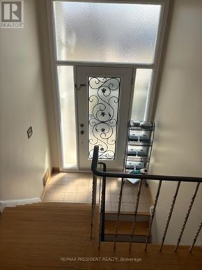 Mississauga (Malton) apartment for rent - A staircase with a metal railing leads to a door with a decorative glass panel.