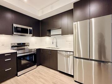 Surrey apartment for rent - A modern kitchen with dark brown cabinets and stainless steel appliances.