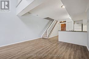 Ottawa multi-family for rent - A spacious room with wooden flooring and a staircase leading to the upper level.