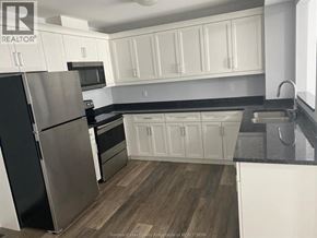 Lakeshore apartment for rent - A kitchen with white cabinets and a black fridge.