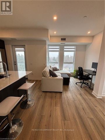 Waterloo condo for rent - A well-lit living room with a white couch and a black office chair.