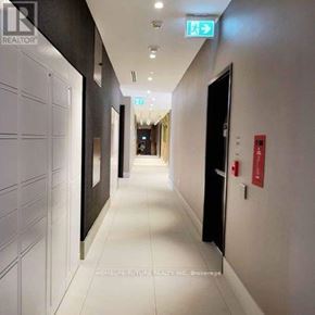 Oshawa (Windfields) condo for rent - A long hallway with a green exit sign on the wall.