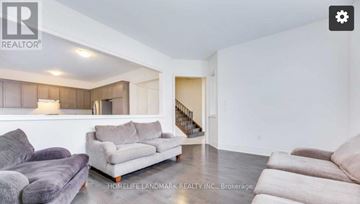 Oakville (Jm Joshua Meadows) apartment for rent - A living room with a grey couch and a wooden cabinet.