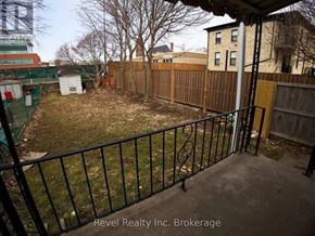 Woodstock (Woodstock - South) triplex for rent - A backyard with a black fence and a green building in the background.