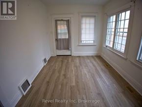 Woodstock (Woodstock - South) triplex for rent - A room with wooden flooring and white walls, with a door and two windows.