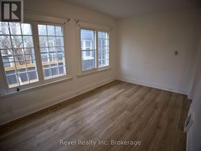 Woodstock (Woodstock - South) triplex for rent - A room with wooden floors and white walls, with windows on the left side.