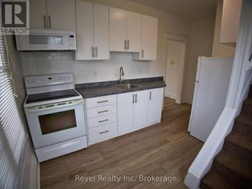 Woodstock (Woodstock - South) triplex for rent - A kitchen with white cabinets and appliances is for sale.
