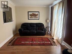 Brampton (Heart Lake West) apartment for rent - A living room with a black couch and a red rug.