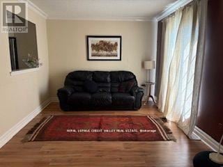 Brampton (Heart Lake West) apartment for rent - A living room with a black couch and a red rug.