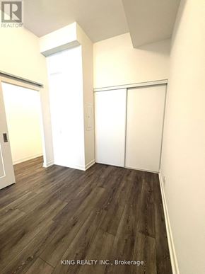 Toronto (Birchcliffe-Cliffside) condo for rent - A room with wooden flooring and white walls, with a sliding door and a window.