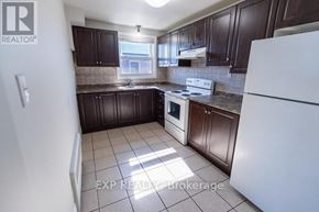 St. Catharines (E. Chester) multi-family for rent - A kitchen with brown cabinets and a white refrigerator.