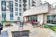 Ottawa condo for rent - A patio with chairs and a table is in front of a building.