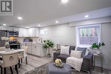 Hamilton (Burkholme) apartment for rent - A well-lit living room with a grey couch and a dining table set up.