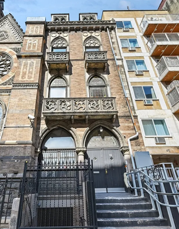 New York apartment for rent - A tall building with a balcony and a gate in front of it.