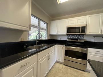 Honolulu apartment for rent - A kitchen with white cabinets and black countertops.