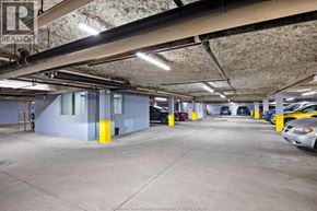 Windsor apartment for rent - A parking garage with a few cars and a building in the background.