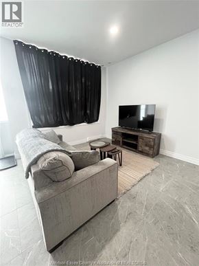 Windsor apartment for rent - A living room with a grey couch, a television, and a wooden coffee table.