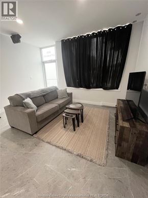 Windsor apartment for rent - A living room with a grey couch, a small table, and a television.