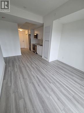 Clarington (Bowmanville) condo for rent - A real estate listing photo of a large empty room with wood flooring and white walls.