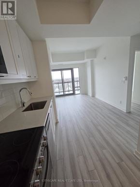 Clarington (Bowmanville) condo for rent - A kitchen with white cabinets and a black stove top oven.
