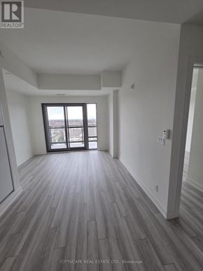 Clarington (Bowmanville) condo for rent - A spacious room with wood flooring and a large window.