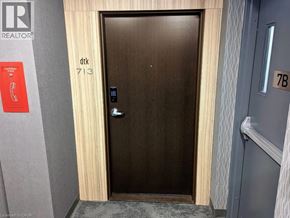 Kitchener condo for rent - A brown door with a silver handle and a sign on the wall above it that says "REALTOR".