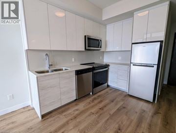 Kitchener condo for rent - A kitchen with white cabinets and a wooden floor.