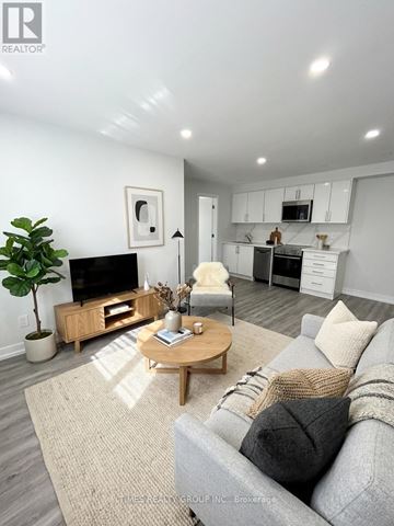 Toronto (Annex) multi-family for rent - A living room with a grey couch, a wooden coffee table, and a TV on the wall.