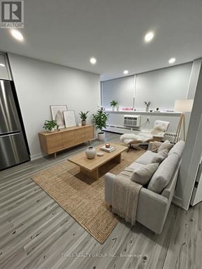 Toronto (Annex) multi-family for rent - A modern living room with a grey sofa, wooden coffee table, and a large mirror on the wall.