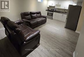 Ajax (Northwest Ajax) apartment for rent - A living room with a brown leather couch and a kitchen area in the background.