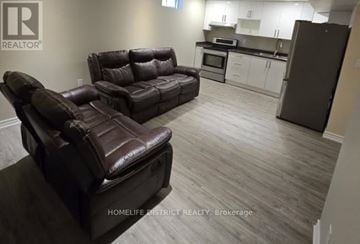 Ajax (Northwest Ajax) apartment for rent - A living room with a brown leather couch and a kitchen area in the background.