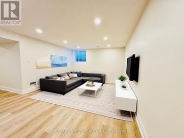 Toronto (Centennial Scarborough) apartment for rent - A modern living room with a black sofa and a television on the wall.