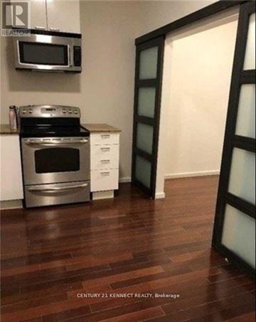 Toronto (Kensington-Chinatown) multi-family for rent - A kitchen with a stove top oven and microwave.
