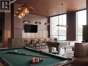 Ottawa apartment for rent - A billiards table is in the middle of a room with a television and chairs.