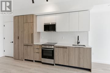 Toronto (Centennial Scarborough) condo for rent - A kitchen with wooden cabinets and a black microwave above the stove.