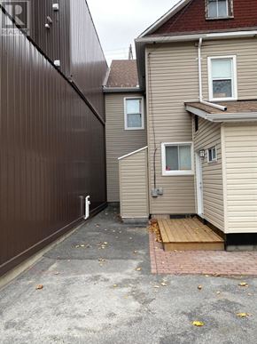 Ottawa townhouse for rent - A brown fence separates a driveway from a house.