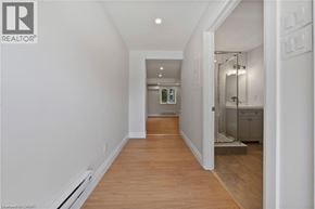 Kitchener apartment for rent - A hallway with a wooden floor and white walls leading to a bathroom.
